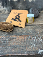 Load image into Gallery viewer, Round Pie Iron & Seasoning Bundle from Rome, including round pie iron, storage cover, seasoning oil, and cleaning brush, displayed on a gray surface - closeup view 3
