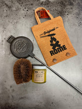 Load image into Gallery viewer, Round Pie Iron & Seasoning Bundle from Rome, including round pie iron, storage cover, seasoning oil, and cleaning brush, displayed on a gray surface - closeup view 2
