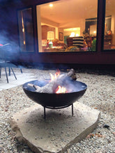 Load image into Gallery viewer, 23.5&quot; Dia. Stamped Steel Fire Pit W/ Grill Grate and Stand Nomadic Grill + Home outside view with fire 2