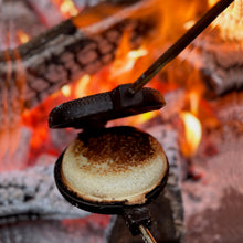 Load image into Gallery viewer, Rome Round Pie Iron close up open view with toasted sandwich over campfire embers